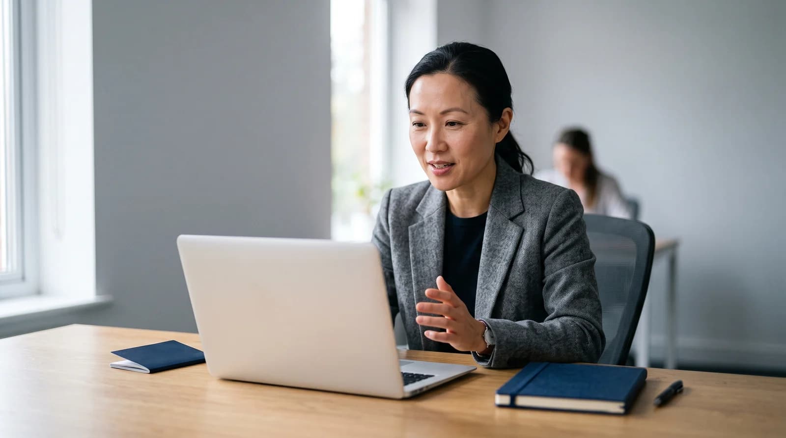 A woman speaking towards an open laptop with a passport beside it, illustrating a remote identity check
